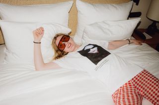 model in a t-shirt with photo from angelica blechschmidt lying on a bed in hotel chateau royal as photographed by christian werner